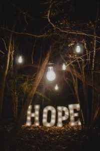 lights hanging from trees above lighted sign that says hope