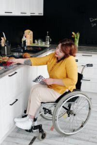 a woman in a wheelchair talking on a cellphone in a kitchen
