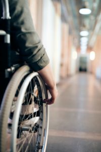 hand on a wheelchair, facing a hallway