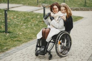 A woman in a wheelchair being hugged by her daughter